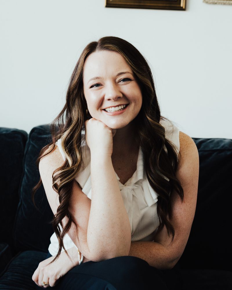 Caitlin Bailey seated on a couch, smiling